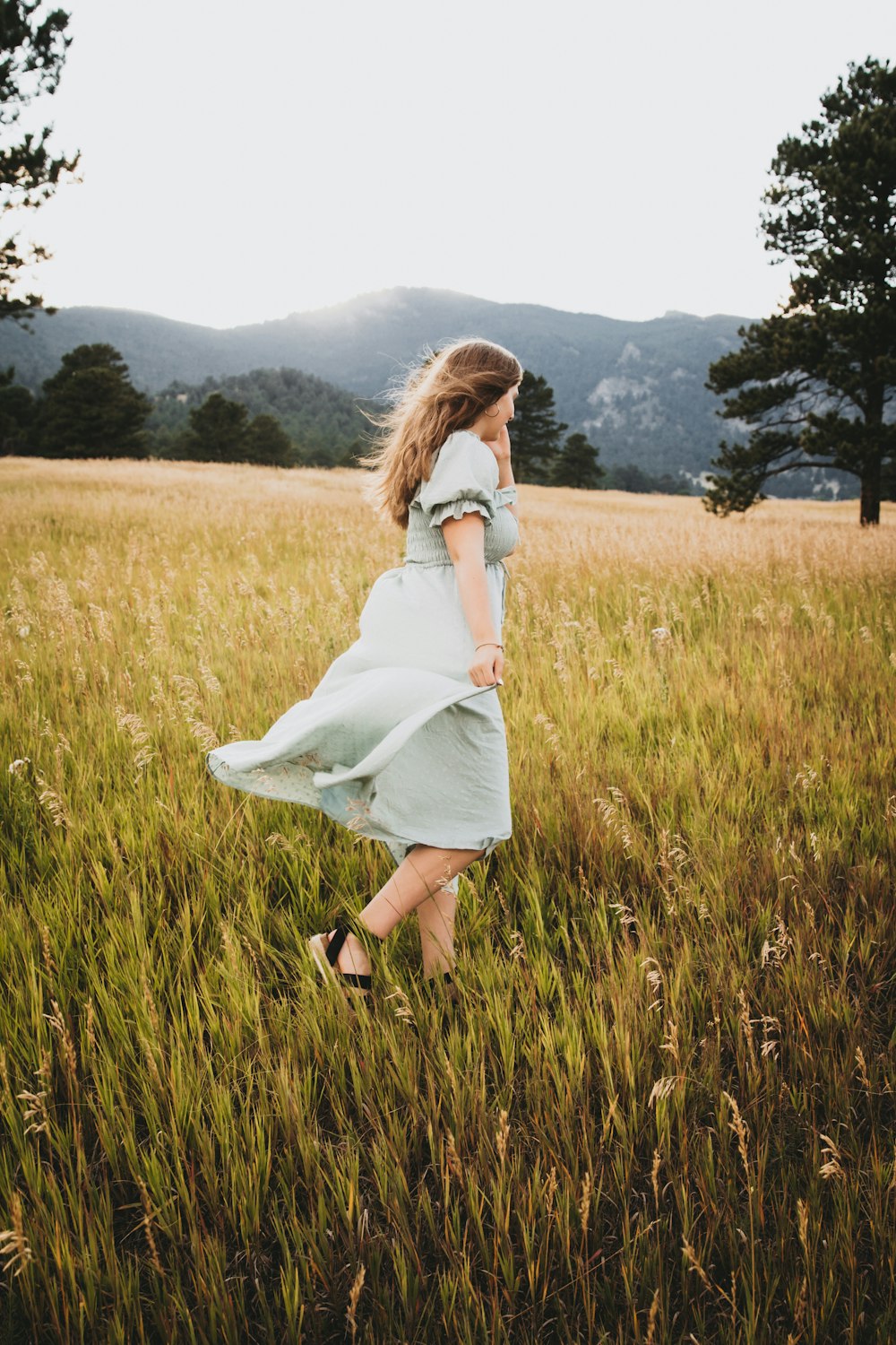 a woman walking through a field of tall grass