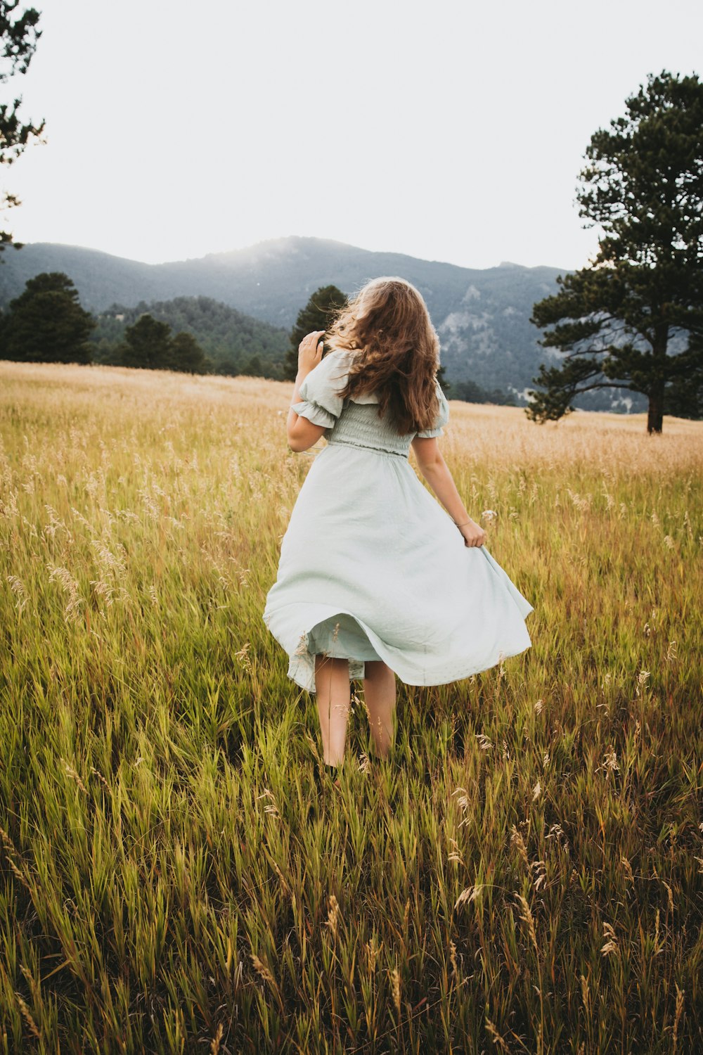 a woman in a dress walking through a field