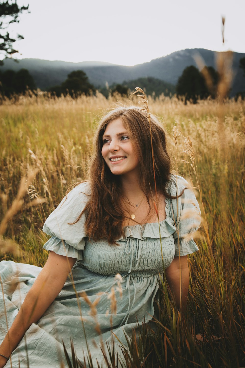 a woman sitting in a field of tall grass