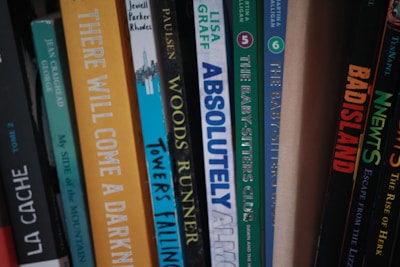A collection of books arranged vertically on a shelf, featuring a variety of titles and colors on their spines.