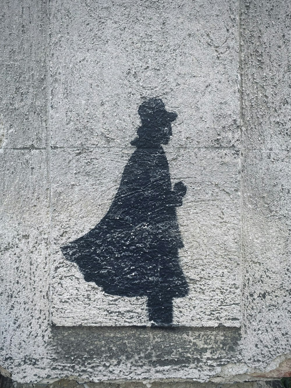 a shadow of a woman in a hat and coat