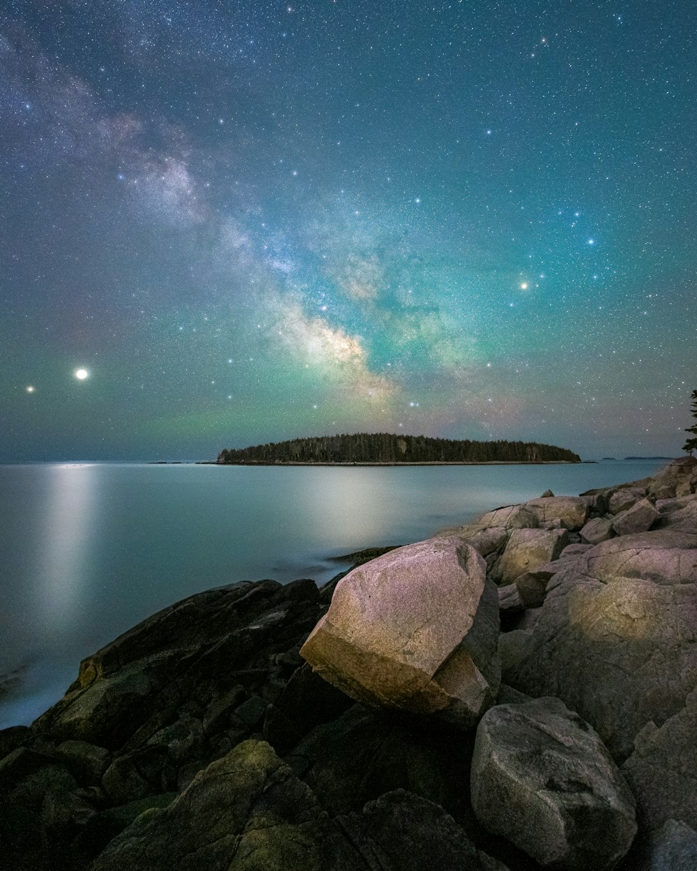 brown rock formation near body of water during night time