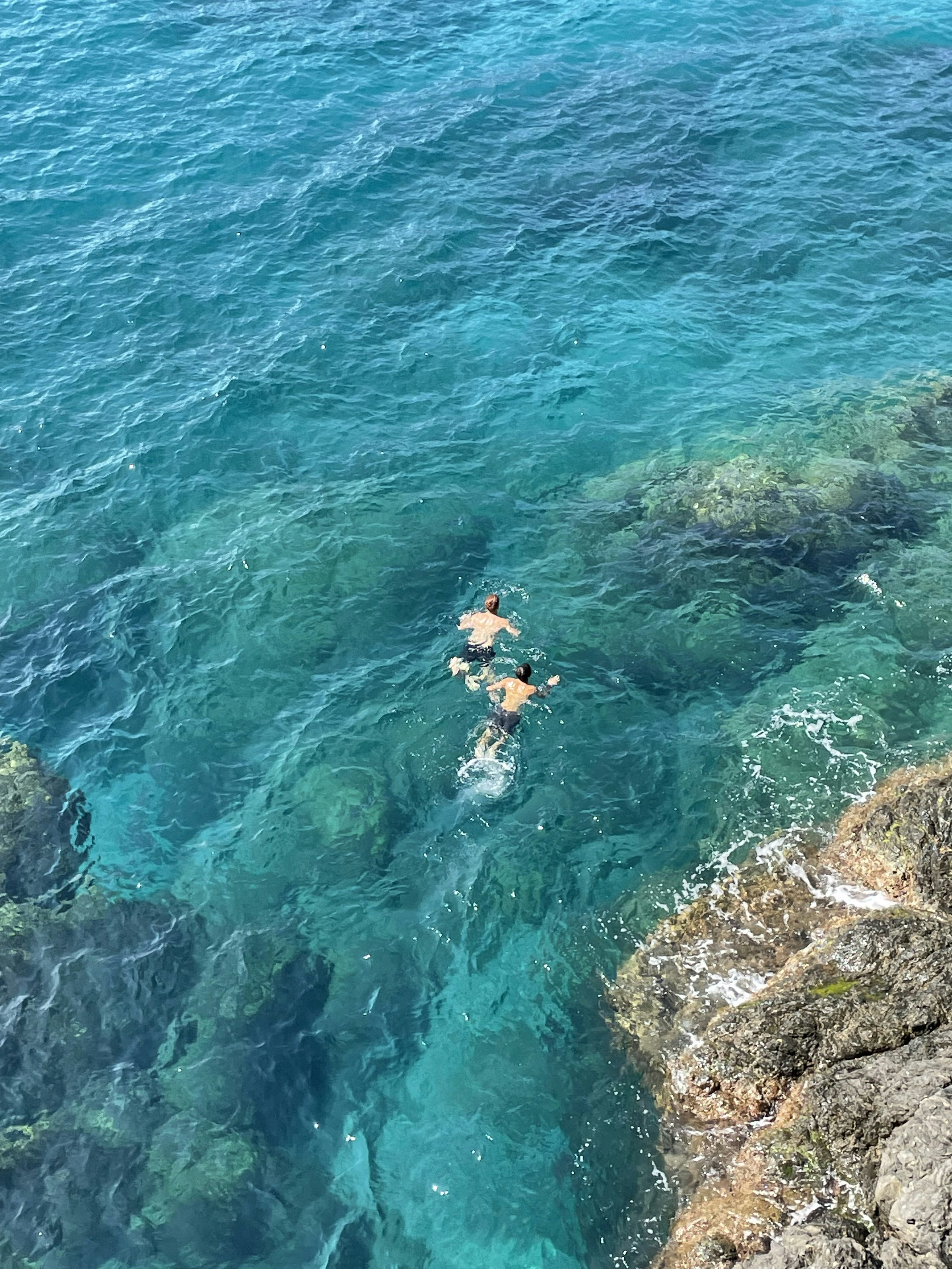 man in blue shorts swimming on blue sea during daytime