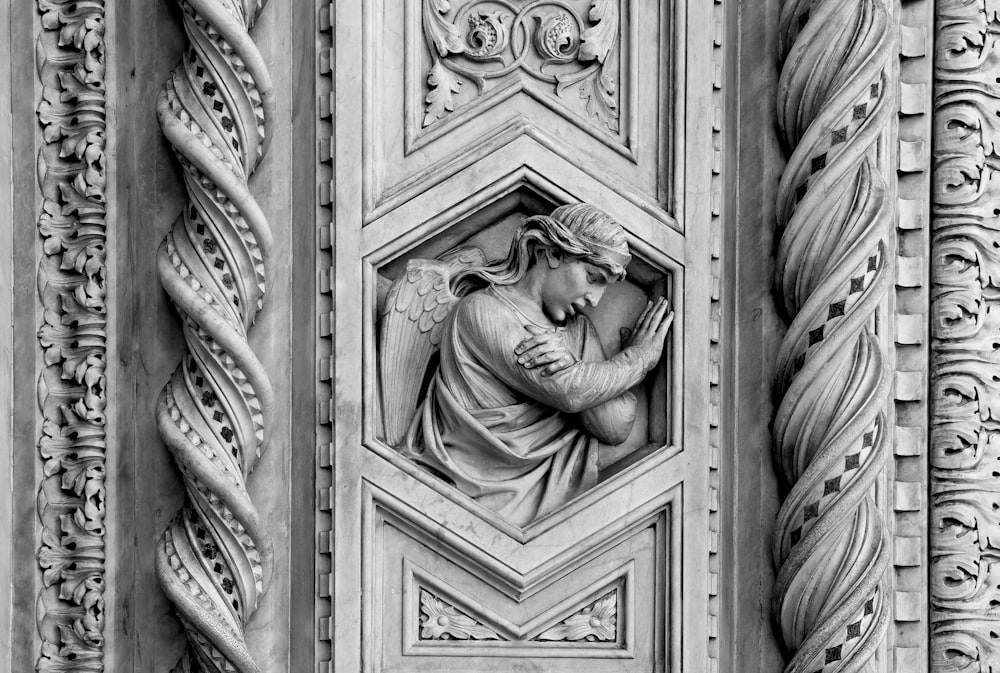 a black and white photo of a statue on a building