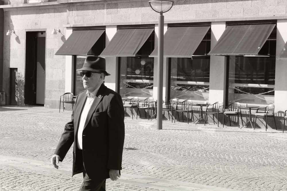 a man in a suit and hat walking down the street