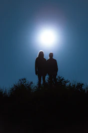 silhouette of man standing on grass field during daytime