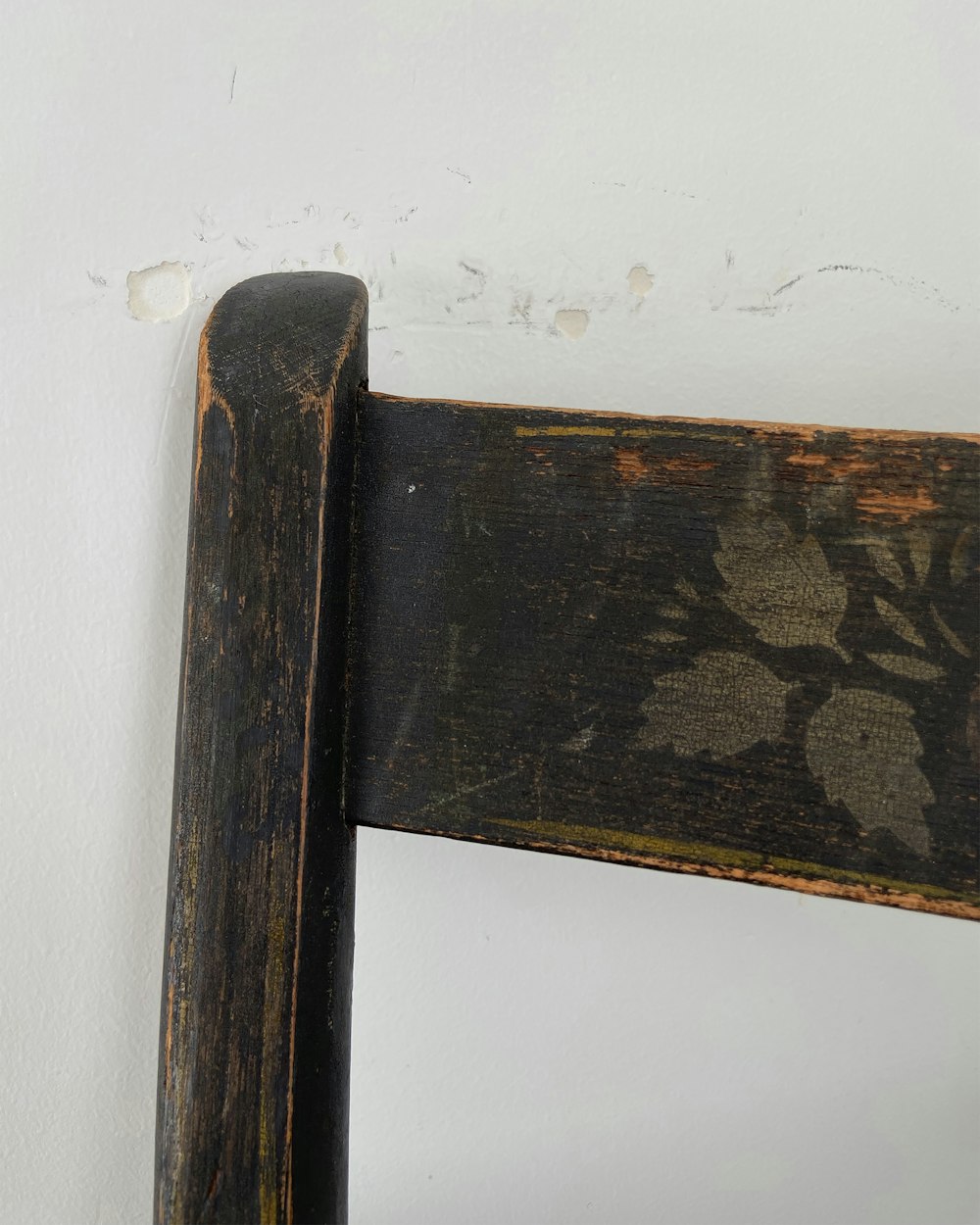 a close up of a wooden chair against a wall