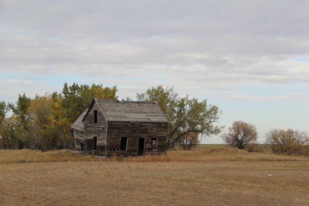 an old house in a field with trees in the background