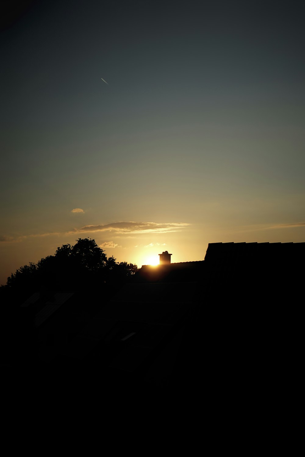 the sun is setting over the roof of a house