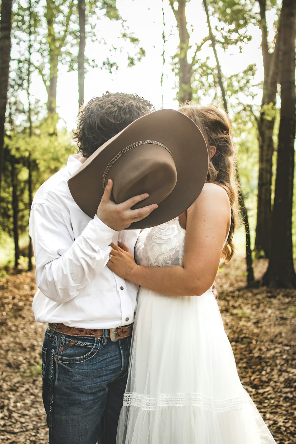 woman in white dress shirt and blue denim jeans holding her hat