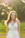 A happy woman wearing a flowing bohemian dress in a sunlit natural setting.