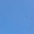 A clear blue sky with a formation of birds flying across. The birds are spaced out and appear to be migrating, stretching across the expanse of the sky.