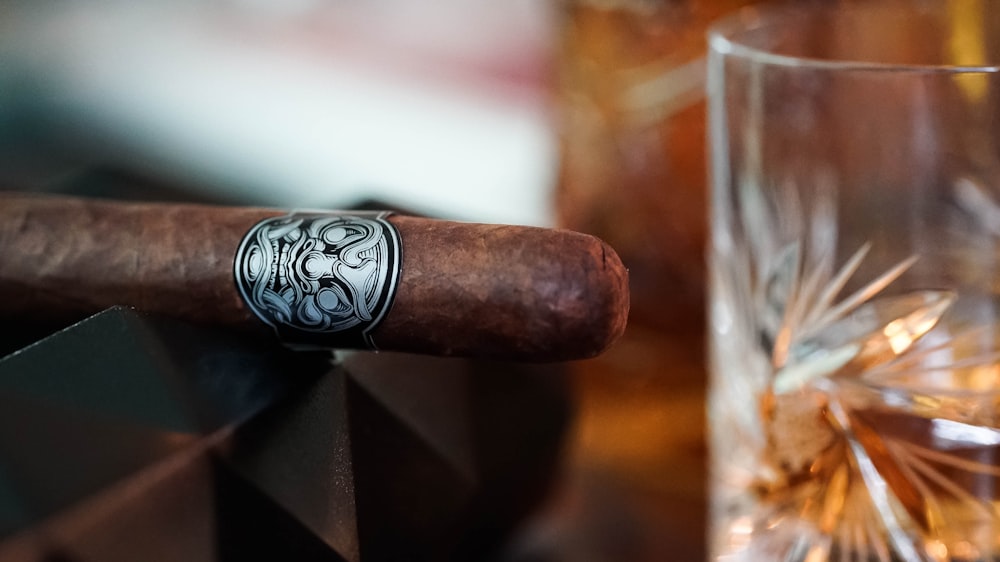 a cigar sitting on top of a wooden table next to a glass