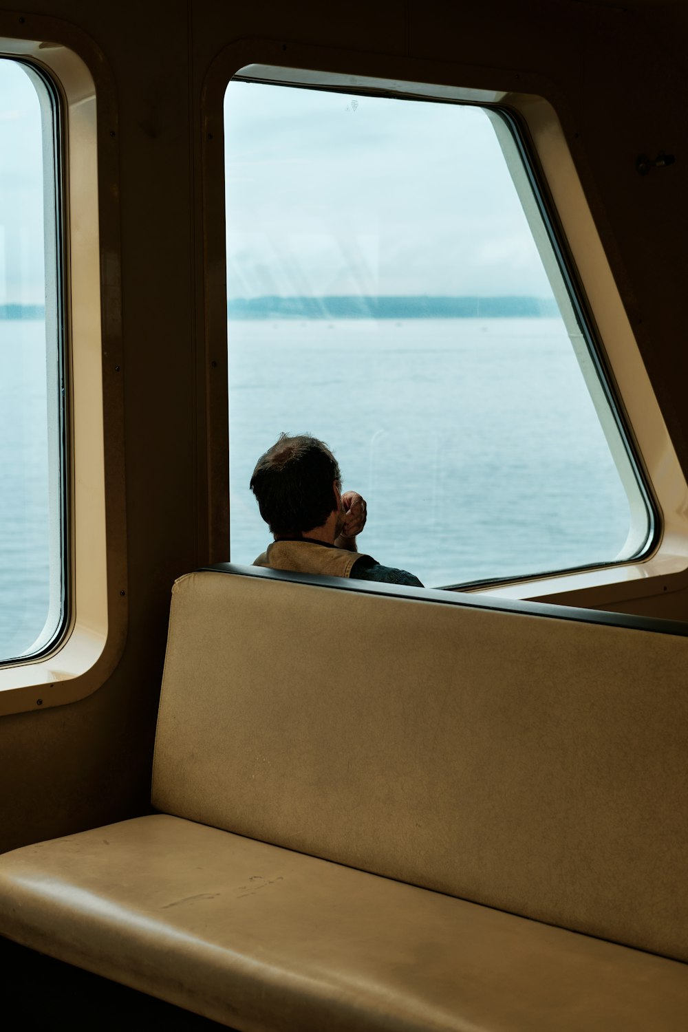 Mujer con camisa negra sentada en la ventana de un barco durante el día