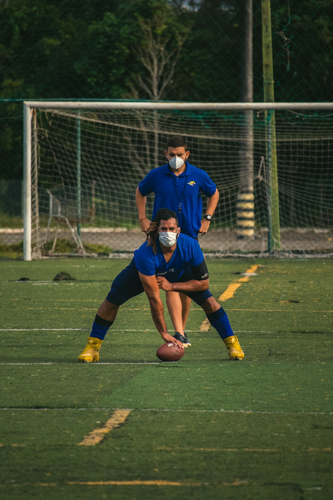 man in blue soccer jersey kicking soccer ball on green grass field during daytime