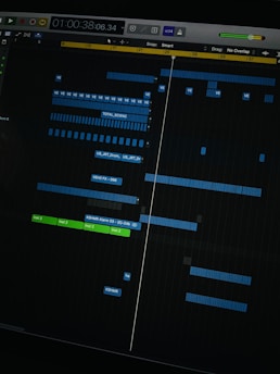 A digital audio workstation interface displaying a timeline with various tracks. Blue and green colored bars represent different audio elements, indicating a complex music project in progress. The interface includes time markers, labels, and controls for editing sound files.