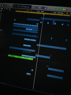 A digital audio workstation interface displaying a timeline with various tracks. Blue and green colored bars represent different audio elements, indicating a complex music project in progress. The interface includes time markers, labels, and controls for editing sound files.