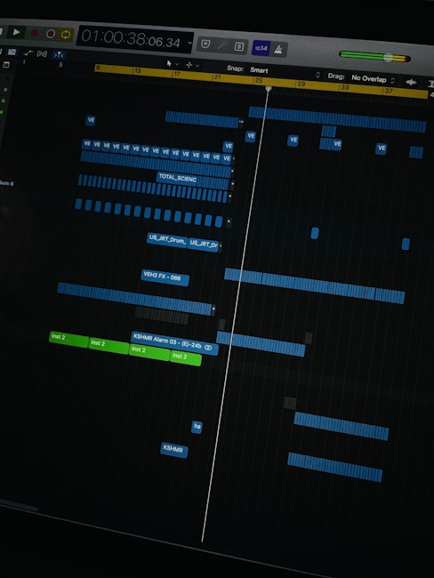 A digital audio workstation interface displaying a timeline with various tracks. Blue and green colored bars represent different audio elements, indicating a complex music project in progress. The interface includes time markers, labels, and controls for editing sound files.