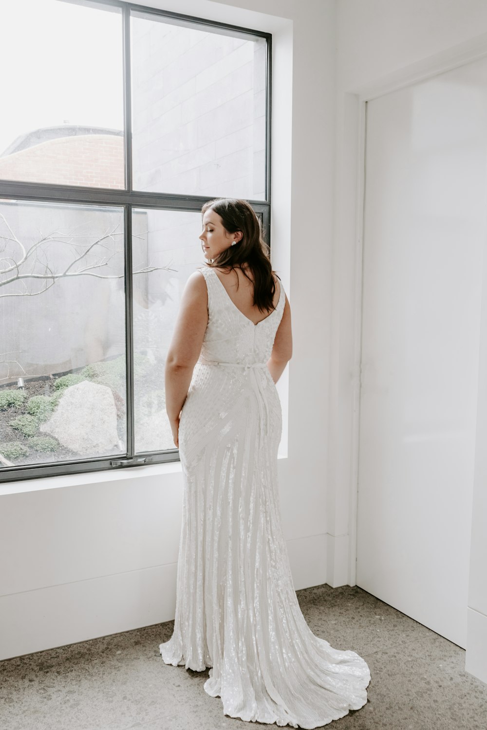 woman in white sleeveless dress standing beside window