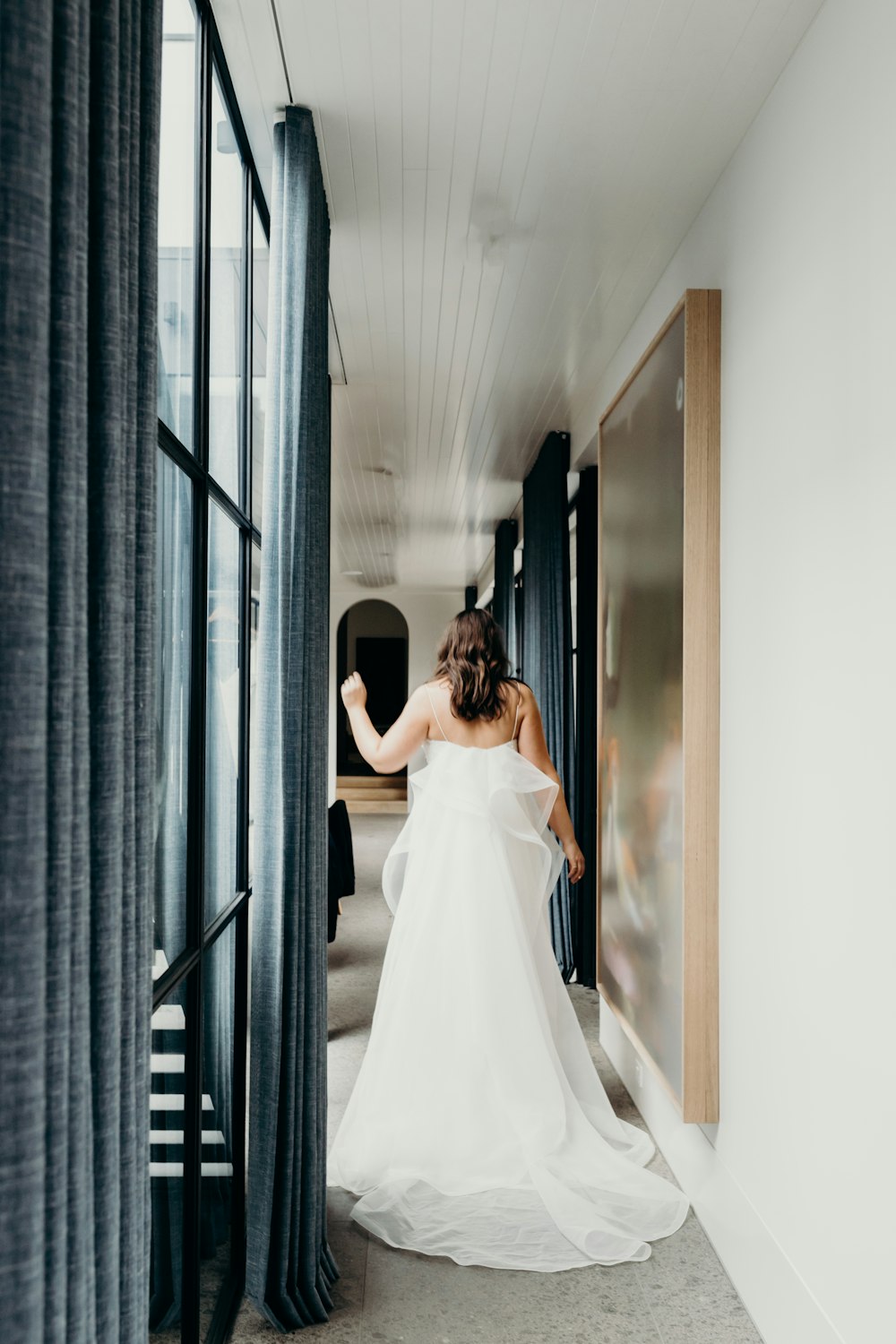 woman in white wedding gown standing in front of mirror
