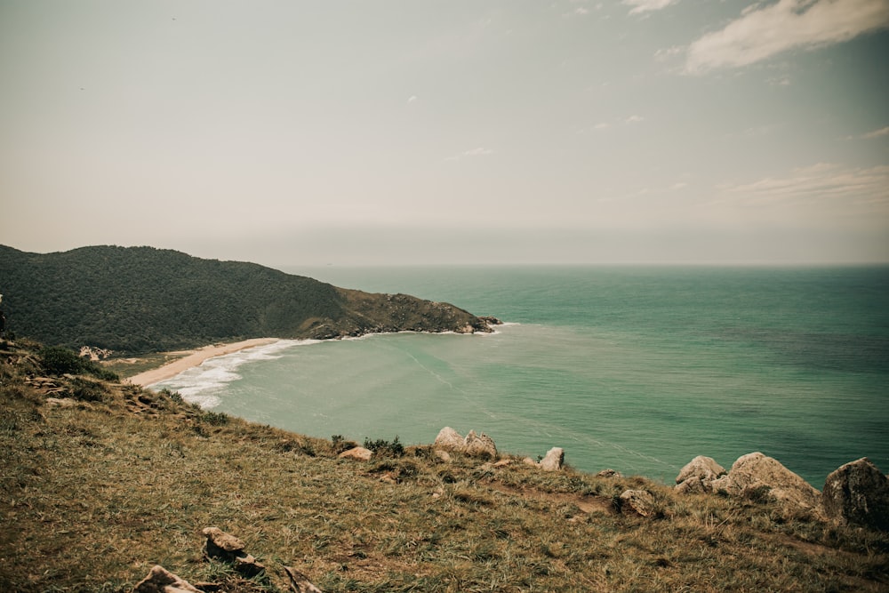 green and brown mountain beside body of water during daytime