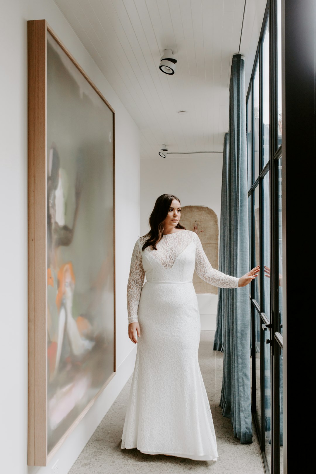 woman in white dress standing beside glass window