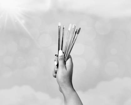 grayscale photo of person holding sticks