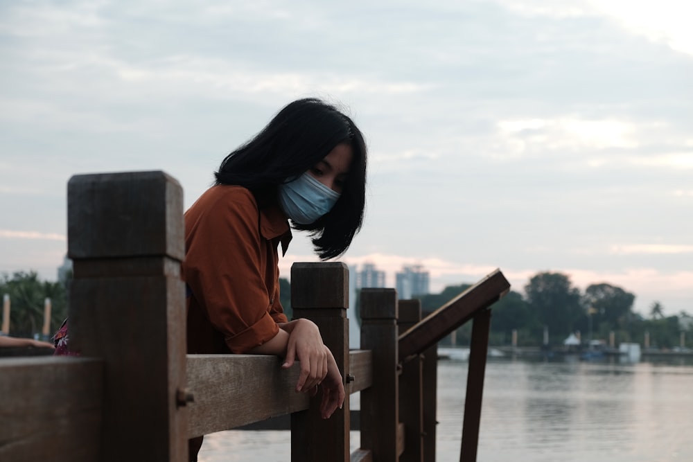 woman in red hoodie standing on wooden dock during daytime