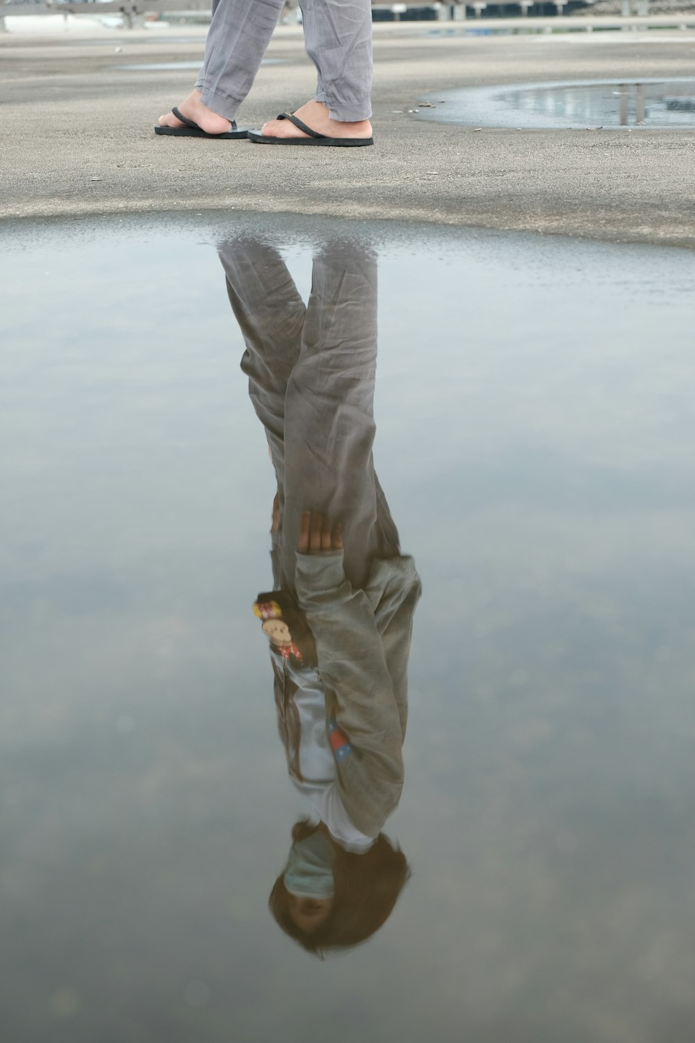 person in gray pants and brown shoes standing on gray sand during daytime