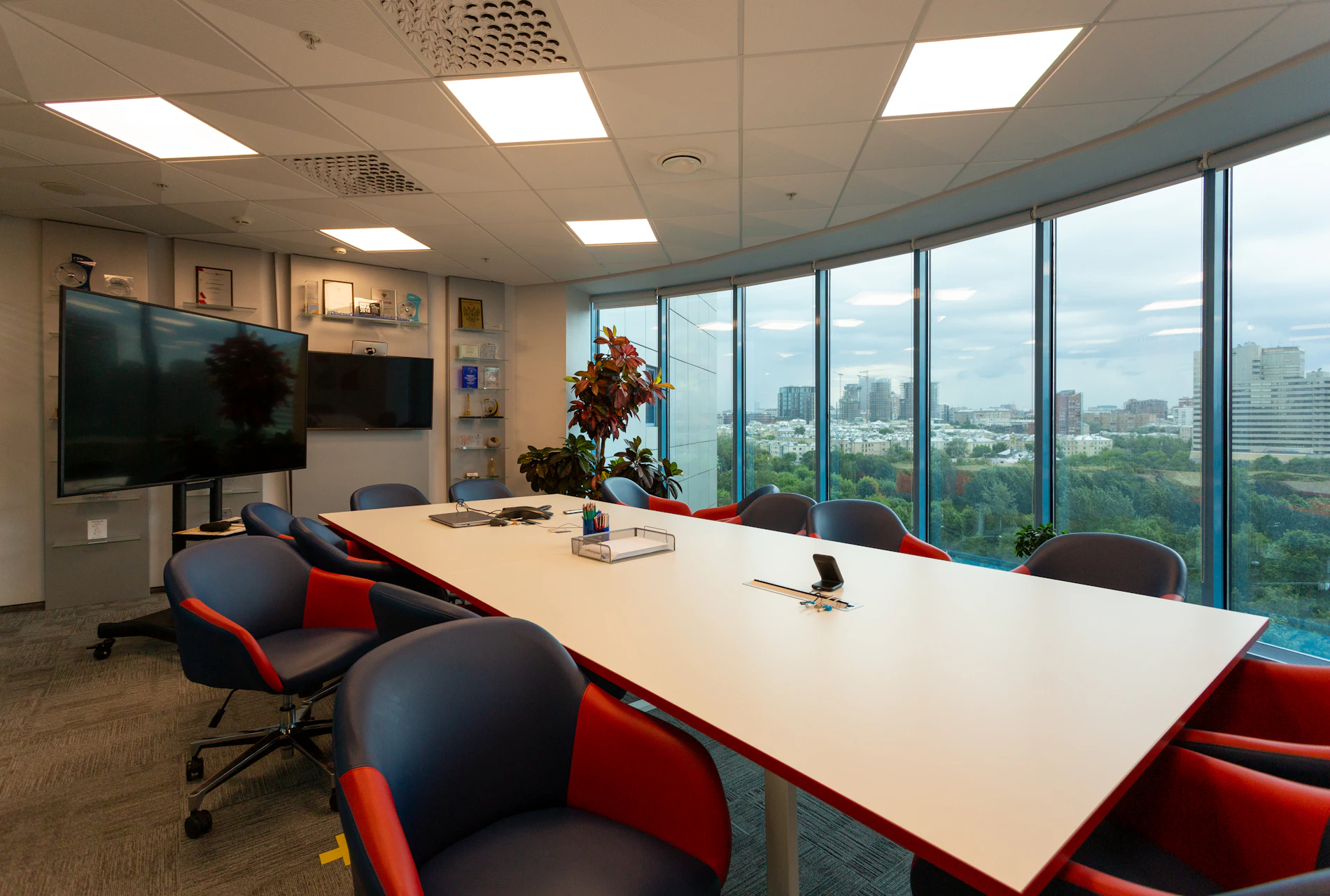 A bright conference room with a long white table and windows on two sides