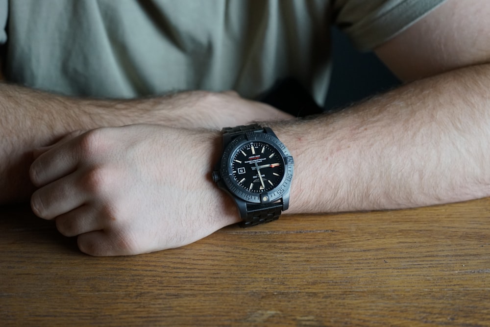 person wearing black and silver round analog watch