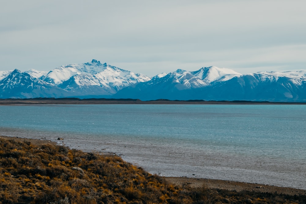 blue body of water near mountain during daytime