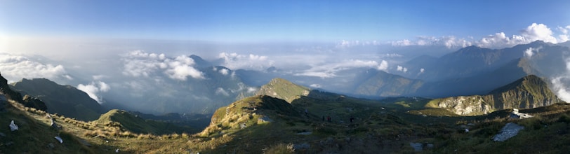 A panoramic mountain view with lush greenery and a winding hiking trail.
