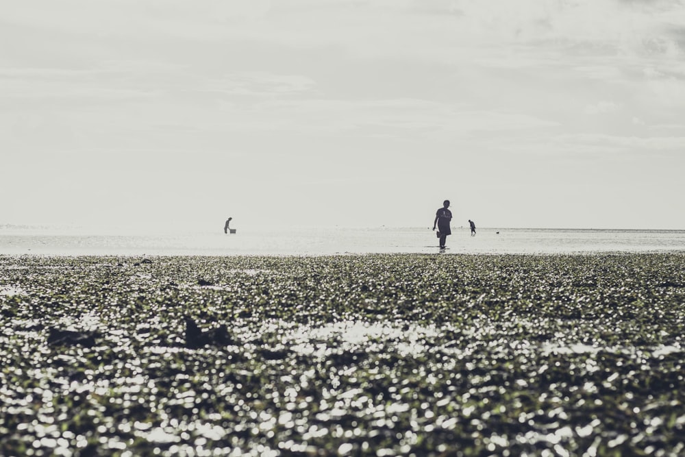 man in black jacket walking on gray sand during daytime