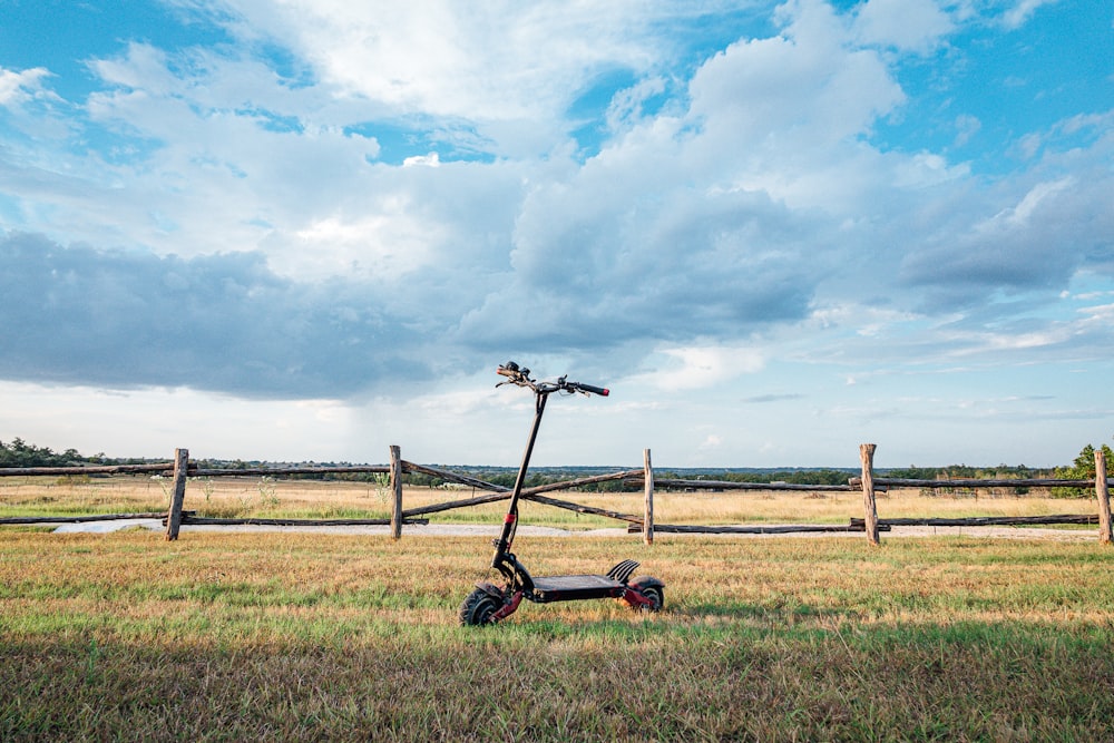 black and red push lawn mower on green grass field under blue and white cloudy sky