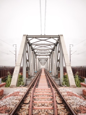 brown metal train rail under white sky during daytime