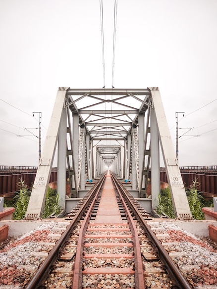 brown metal train rail under white sky during daytime