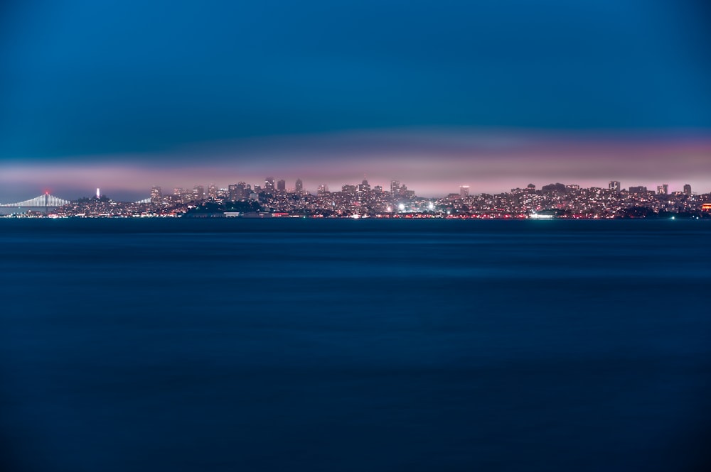city skyline near body of water during night time