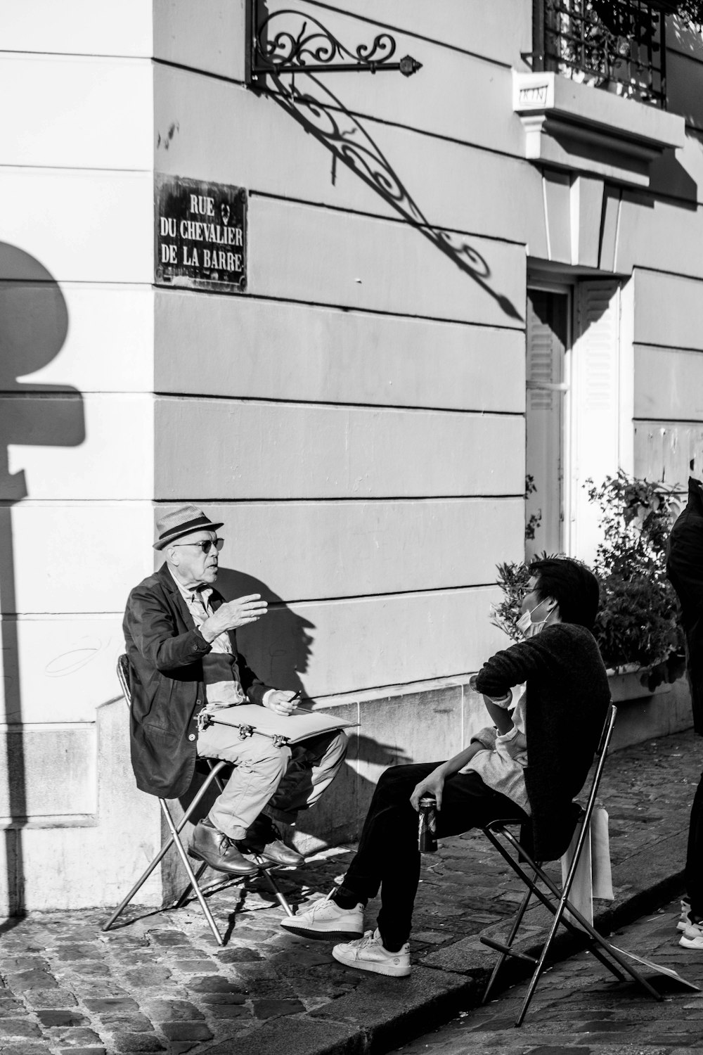 Homme en veste de costume noire et pantalon assis sur une chaise