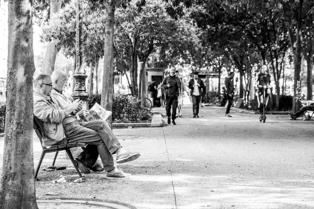 man in jacket sitting on bench in grayscale photography