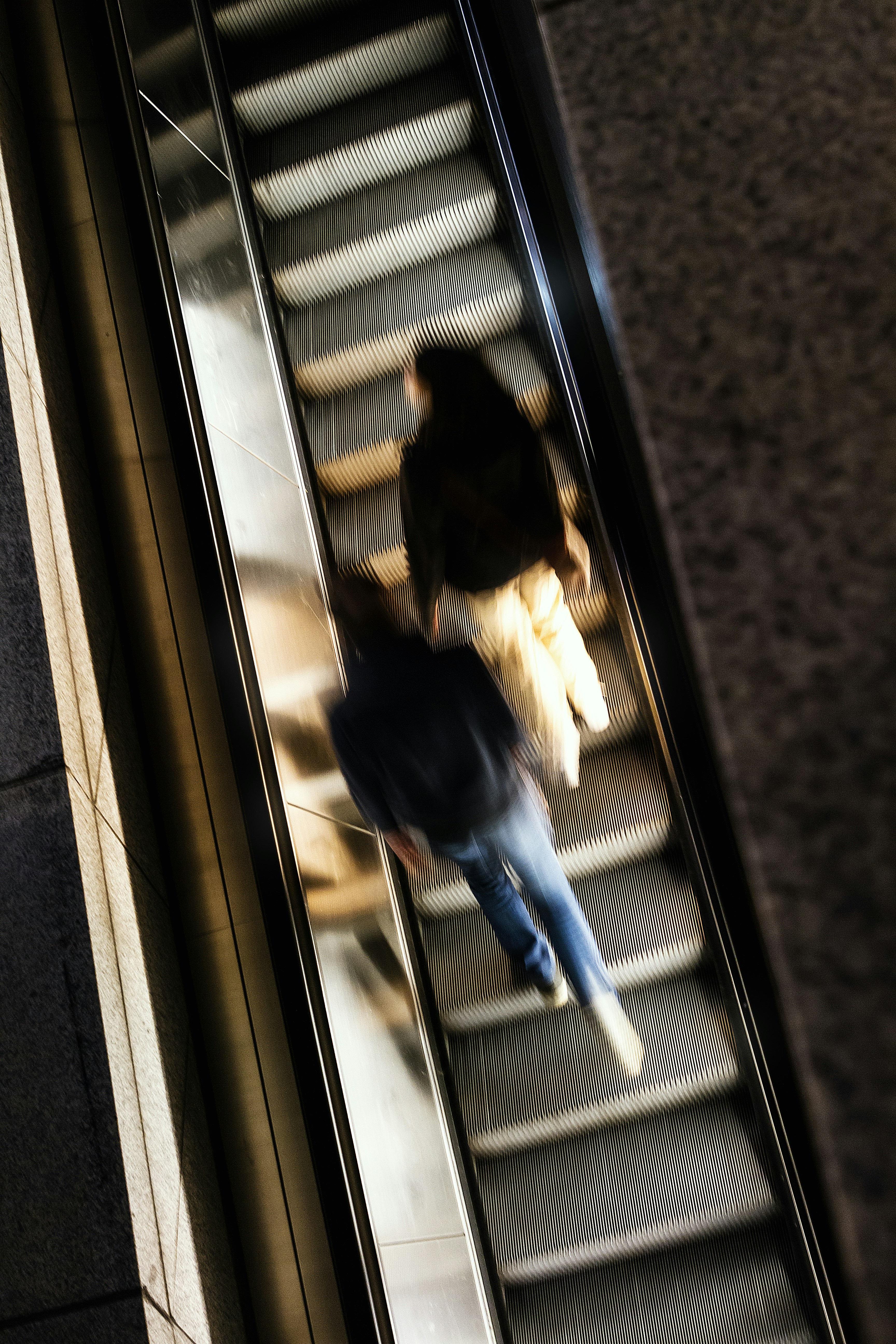 Woman working on a laptop on an escalator.