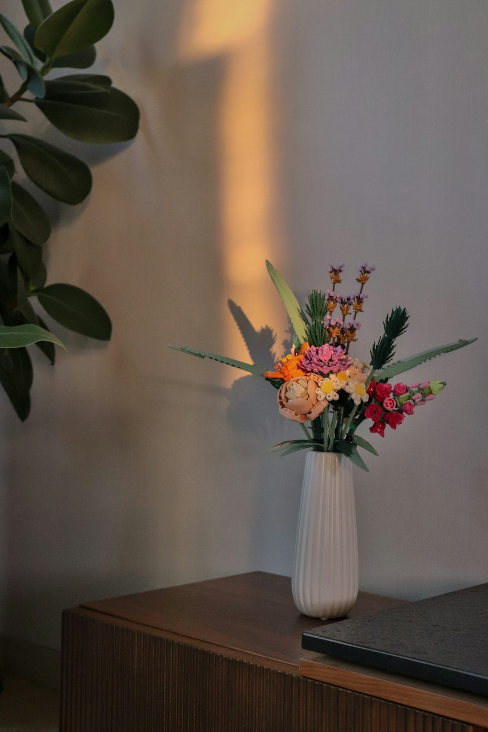 um vaso branco cheio de flores em cima de uma mesa de madeira