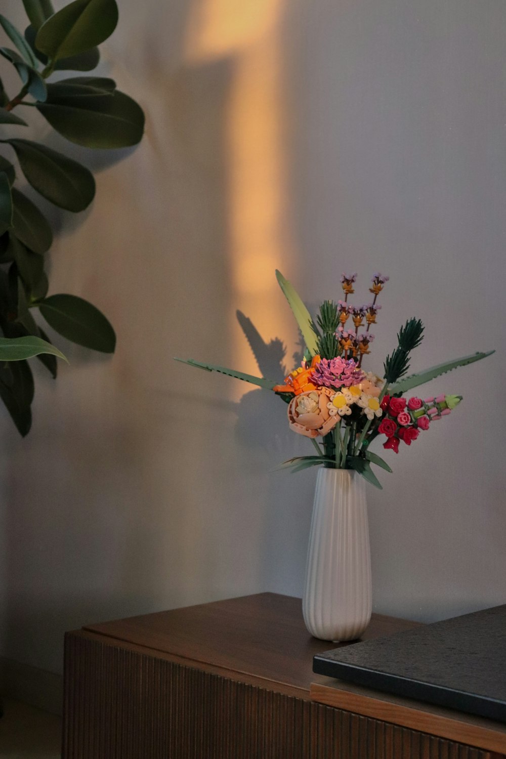 un vase blanc rempli de fleurs sur une table en bois