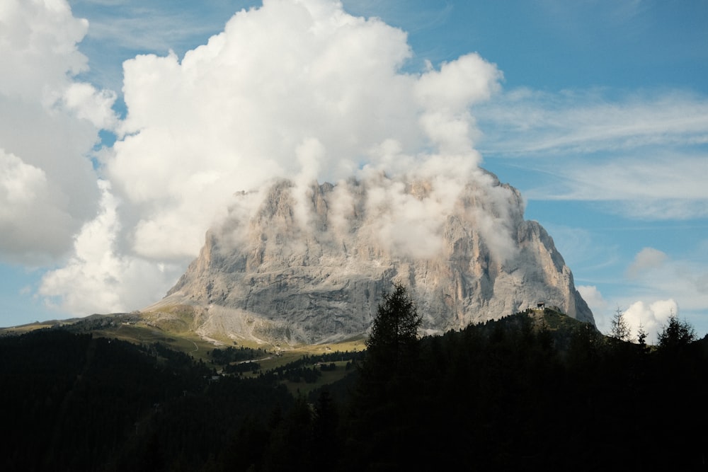 árvores verdes perto da montanha sob nuvens brancas durante o dia