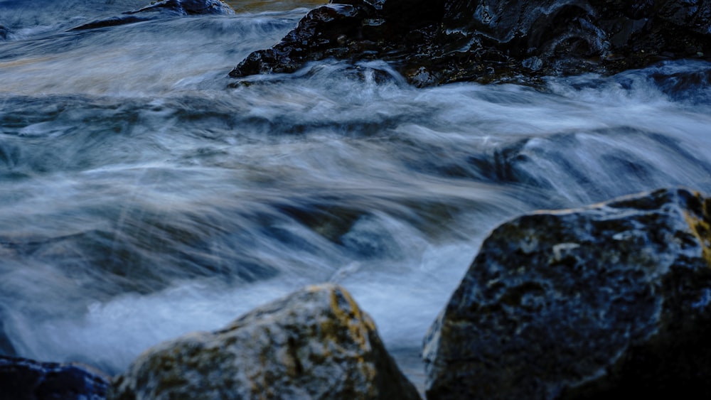 water falls on rocky shore during daytime