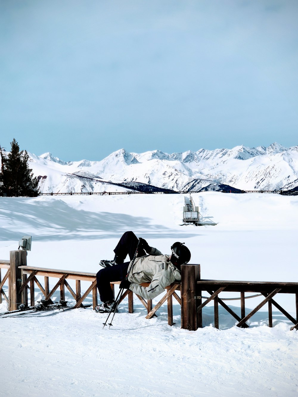 person sitting on brown wooden bench on snow covered ground during daytime