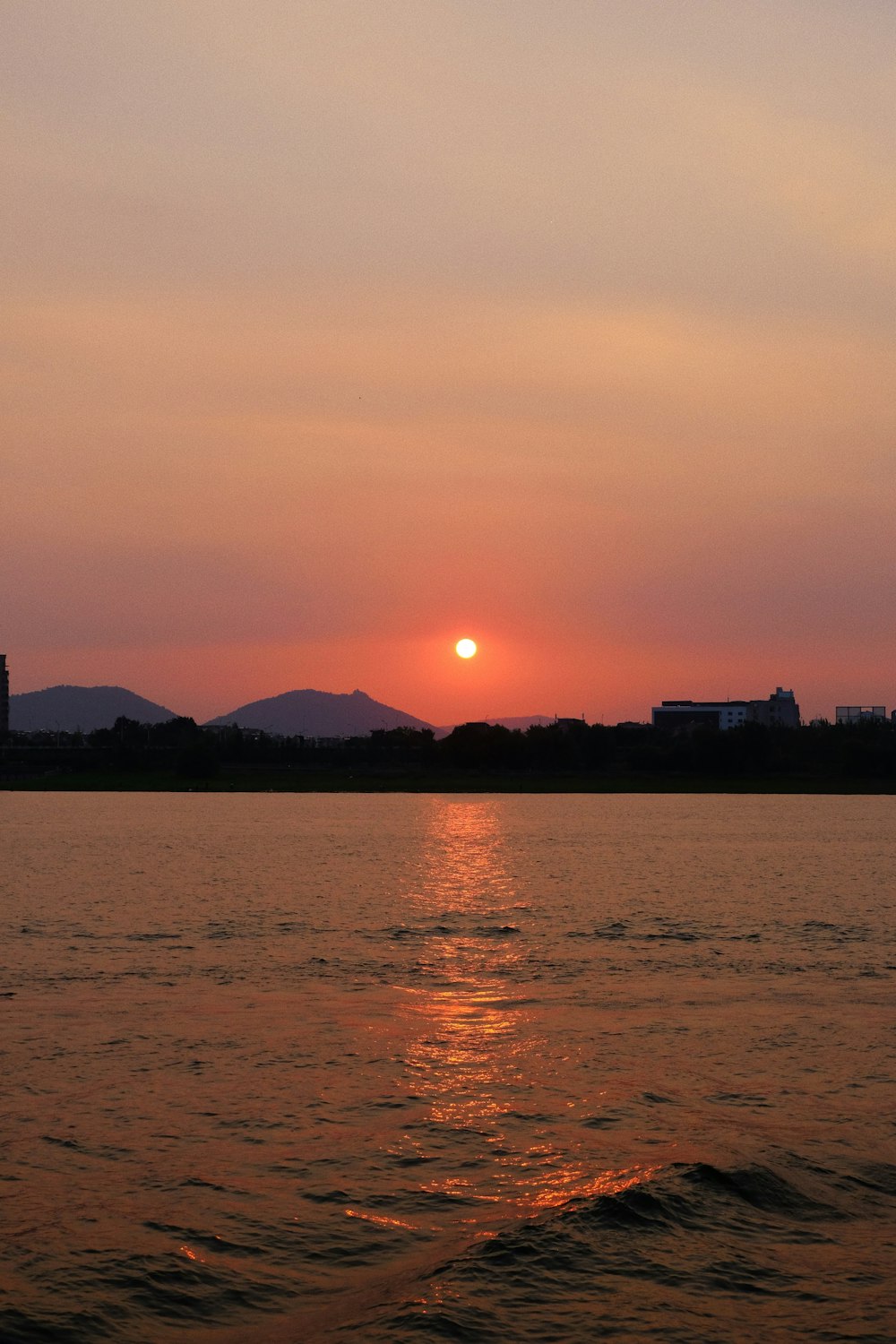 silhouette of building near body of water during sunset