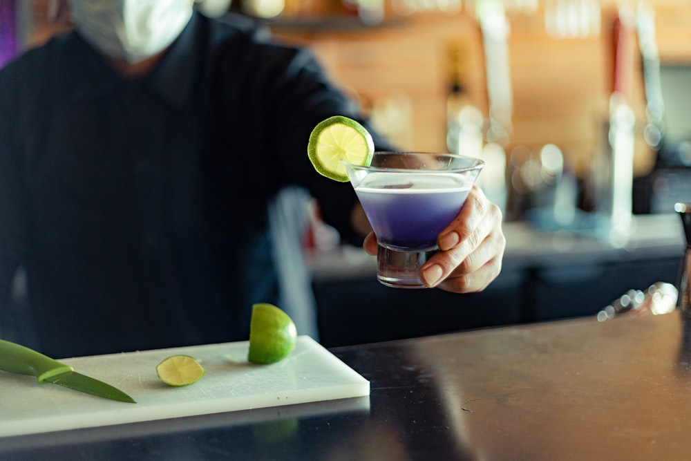 person pouring beverage on clear drinking glass