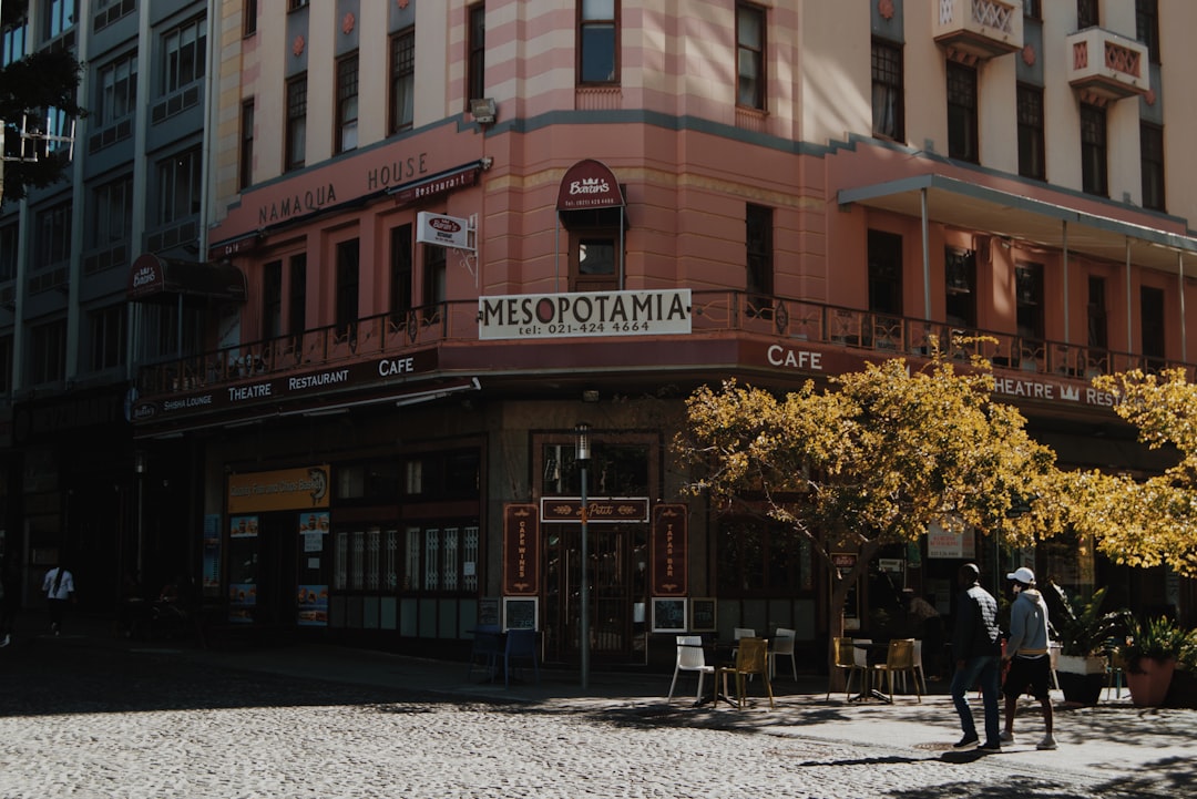 people walking on sidewalk in front of brown concrete building during daytime