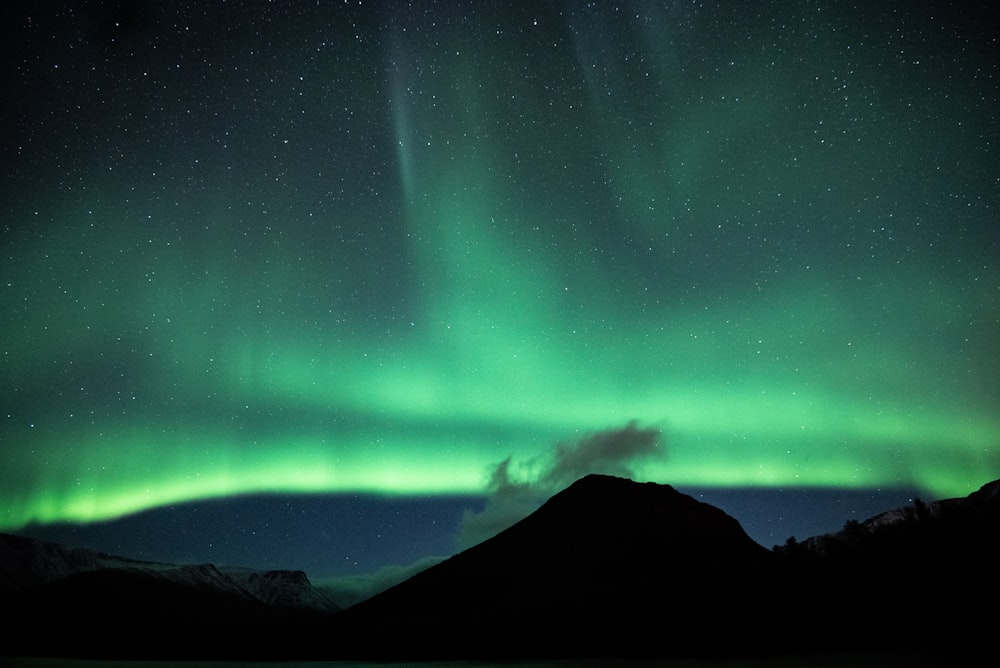 green aurora lights over black mountain